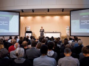 großer Saal mit Publikum und Bühne mit einer Person