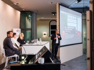 Bühne mit 4 Speaker*innen und Präsentation