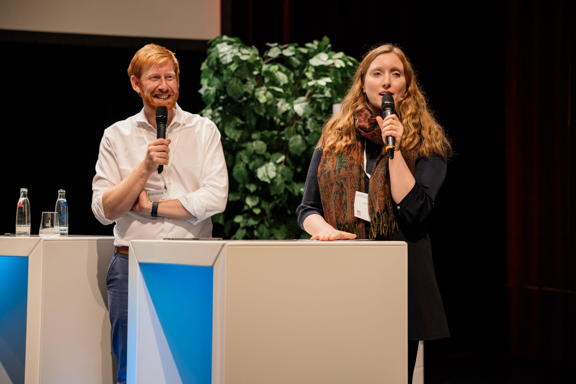 Nora und Tim mit Mikrofonen auf der Bühne, lachend