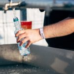 Flasche wird mit Wasser aus dem Hahn aufgefüllt