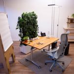 Ein Beispielbüro nach Cradle to Cradle: Tisch, Stuhl. Pflanzenwand, Whiteboard und diverse Büroprodukte auf dem Tisch liegend.