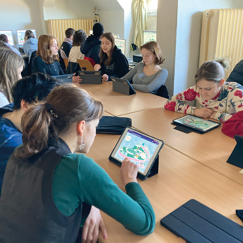 approx. 10 young people sitting at a tablet