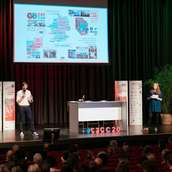 Tim Janßen and Nora Sophie Griefahn, both white and red hair, stand on large stage with audience at Congress 2020, Power Point in background