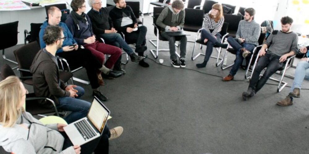 Gruppe Menschen sitzt im Kreis im Innenraum
