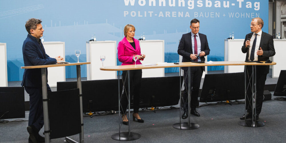 Robert Habeck (links) und drei weitere Personen stehen auf der Bühne und diskutieren.
